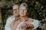 An older couple sitting on a bench in the woods